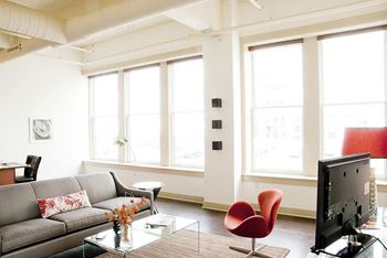 A living room with a grey couch, a red chair, and a television.